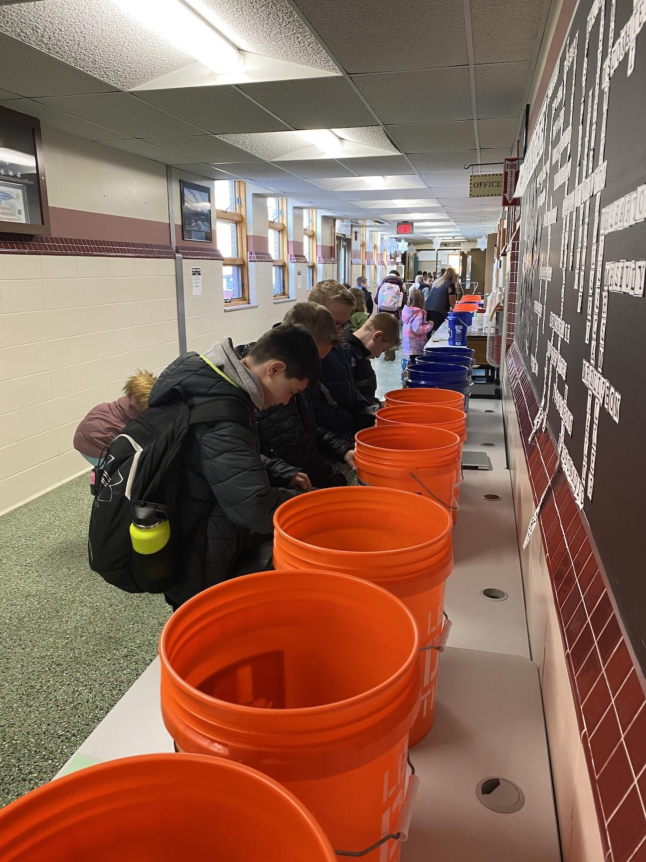 Students gather at the penny war buckets to deposit their coins