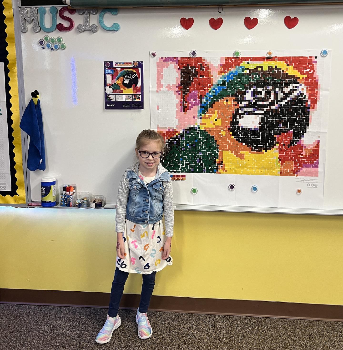 Kindergartener Emma Frescura poses with one of the completed murals