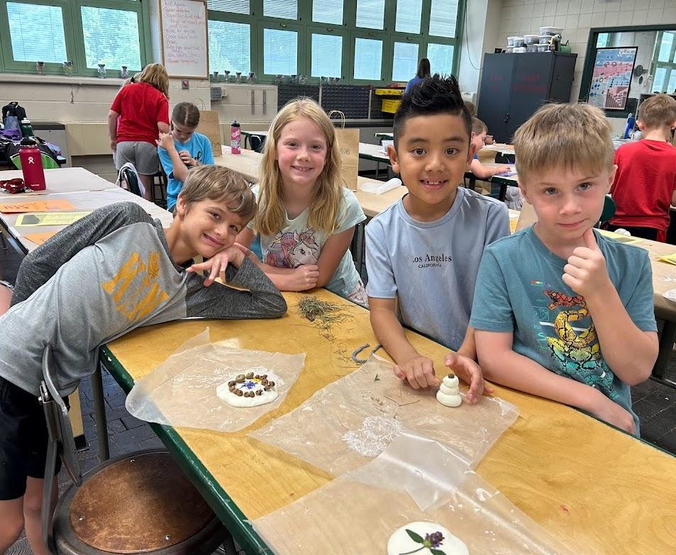 David Govert, Isabelle Govert, Derek Nguyen, and Bryson Mee work on their clay imprints using nature materials found around school grounds