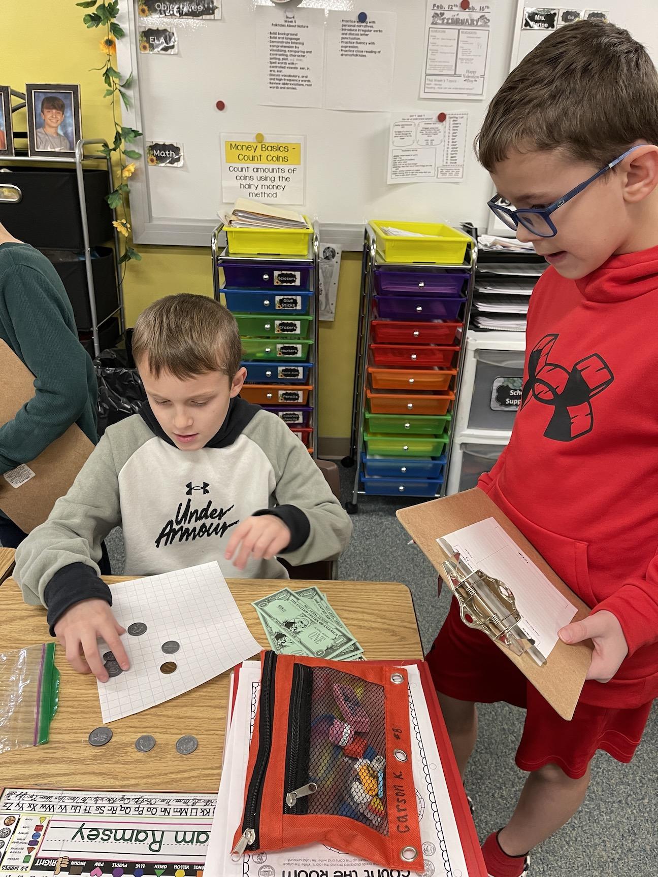 Carson Kalkstein and Brendan Bailey work together on counting money